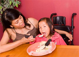 woman feeding child in wheelchair